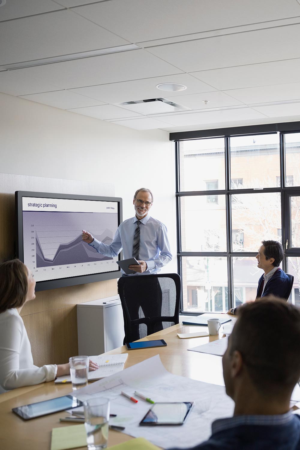 Business professional presenting data on a large touchscreen in a bright boardroom