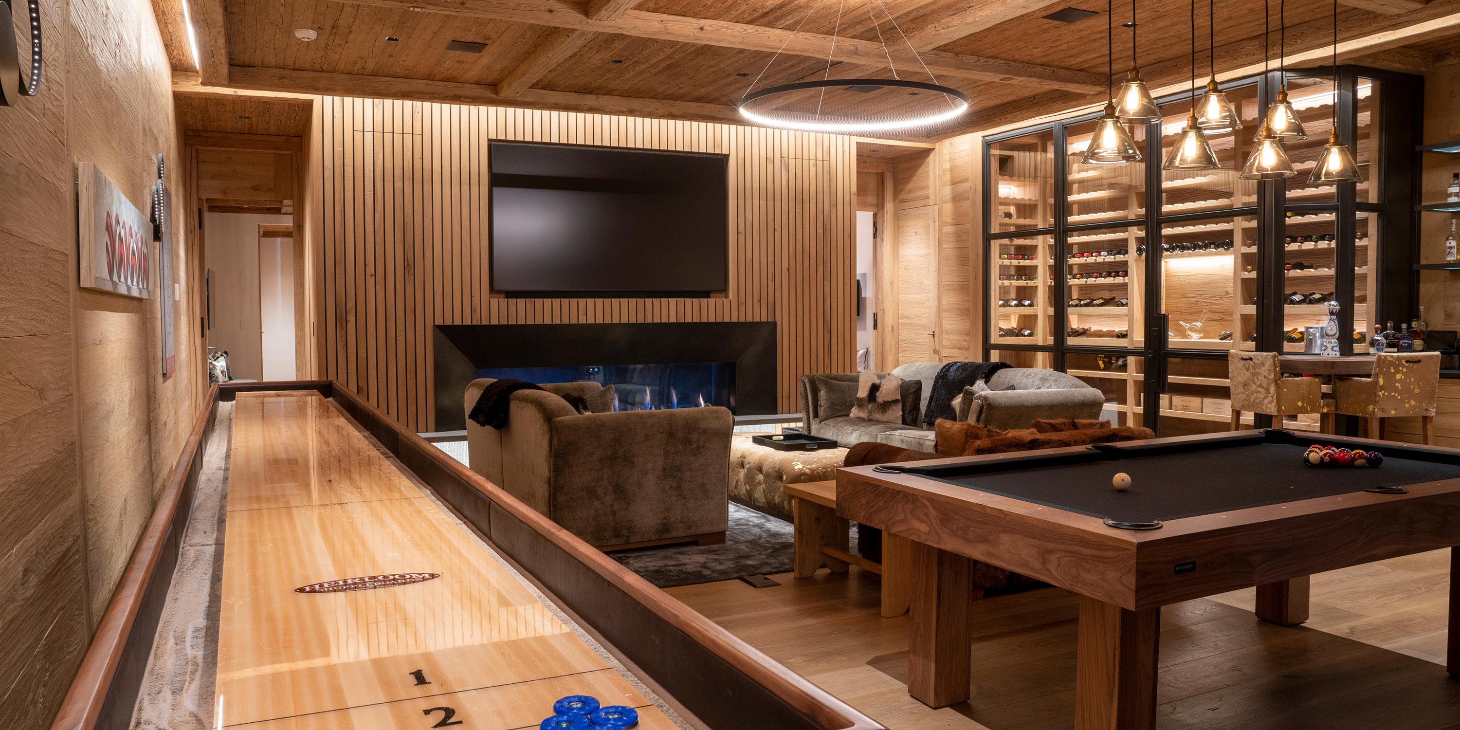 Rustic game room with shuffleboard billiard table and glass wine cellar