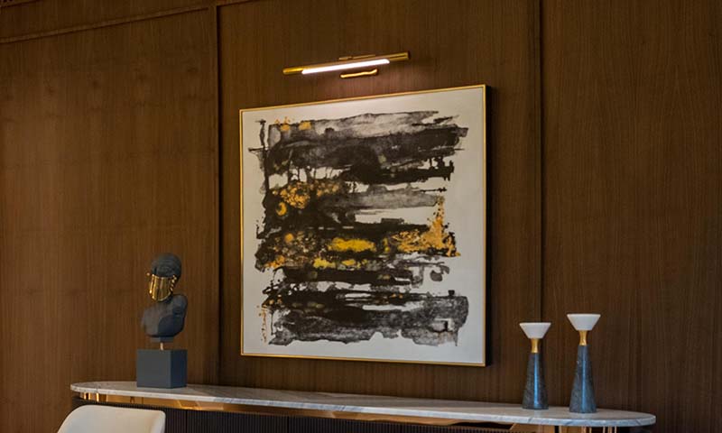 Slim picture light illuminating a piece of wall art