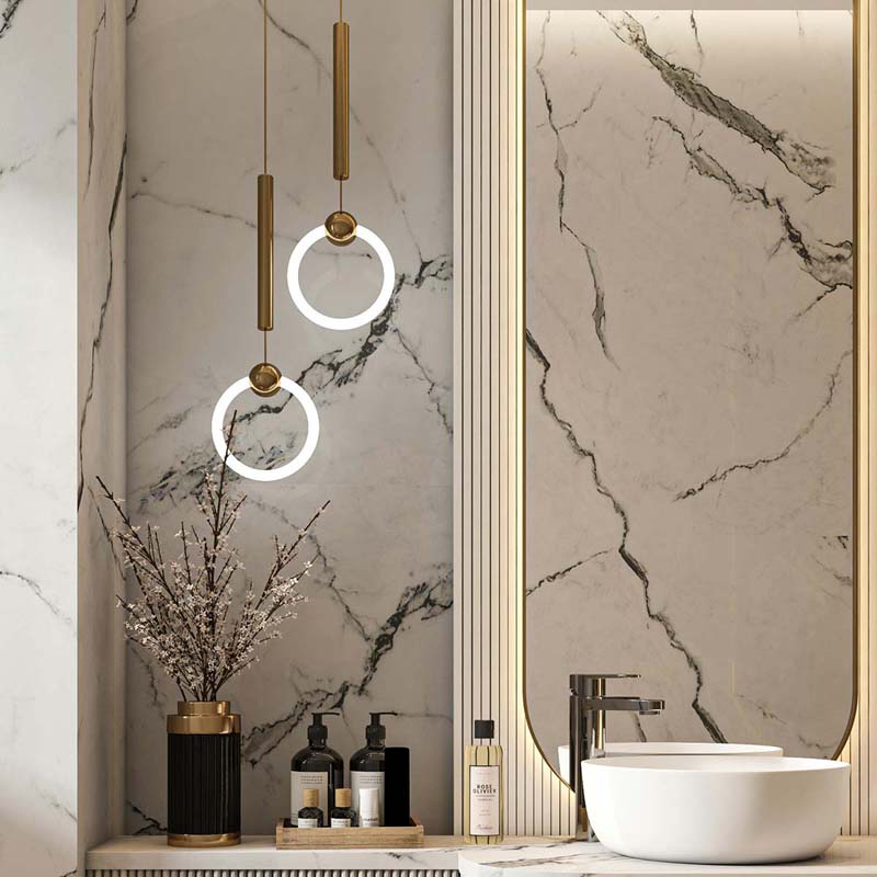 Suspended ring-shaped pendant with integrated LED illumination, placed near a mirror in a marble-finished bathroom.