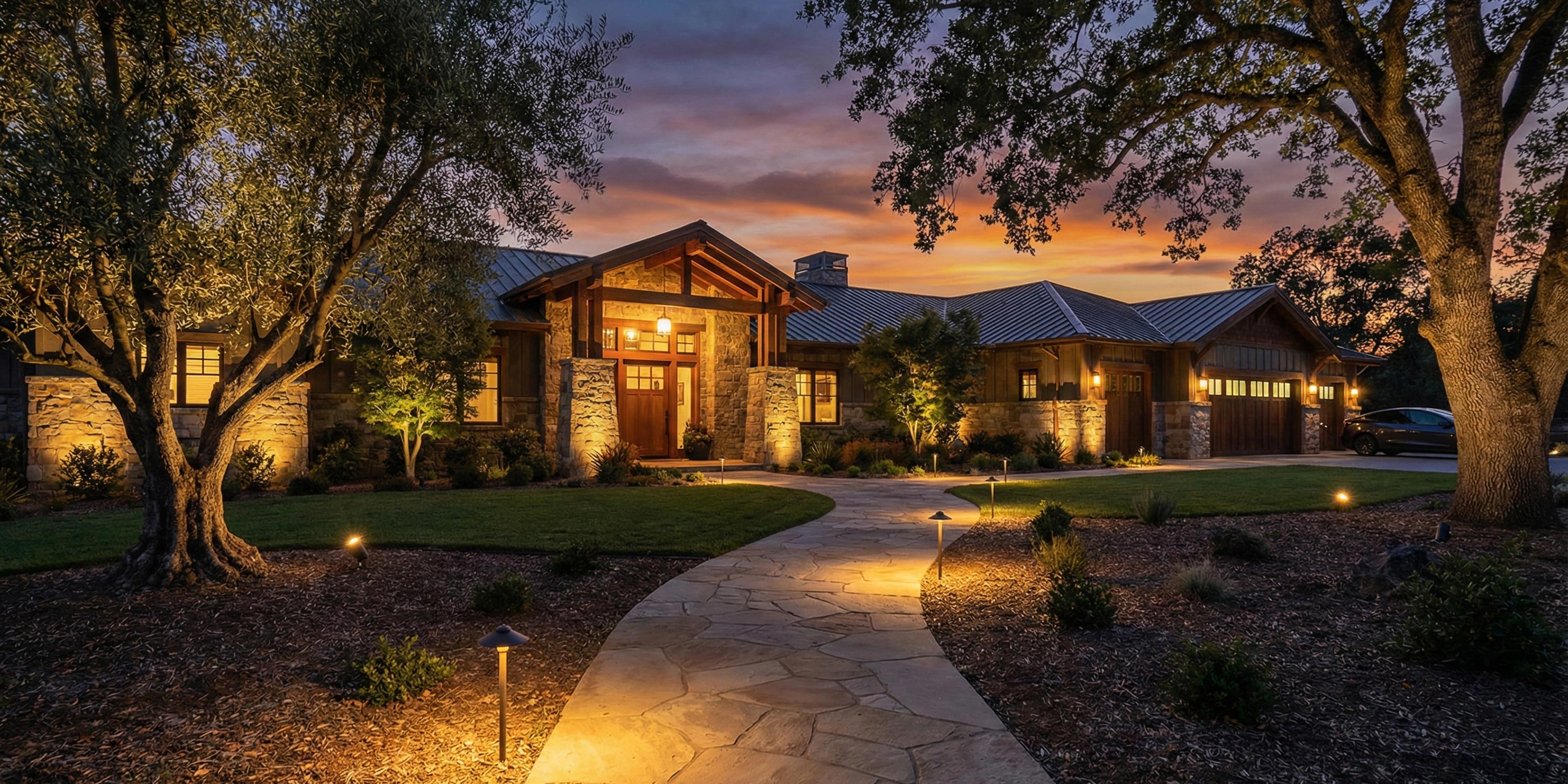 Stone walkway leading to a luxury ranch home with evening accent lighting