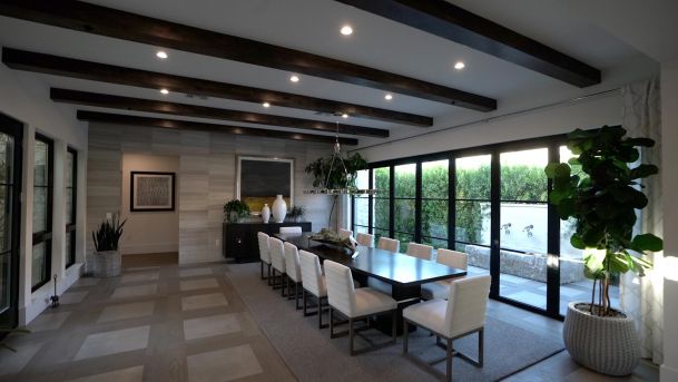 Luxury dining room with dark wood ceiling beams and large black-framed glass doors
