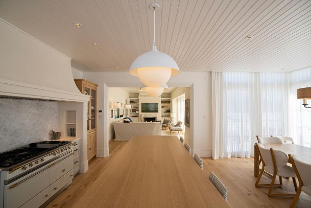 Open concept kitchen and living area with white pendant lights and wood floors