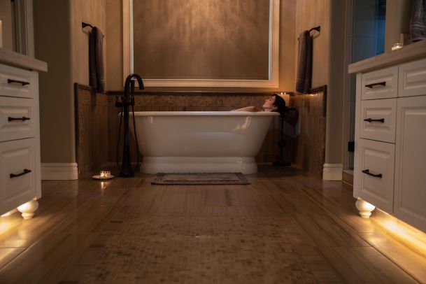 Woman relaxing in a white soaking tub with dim ambient floor lighting