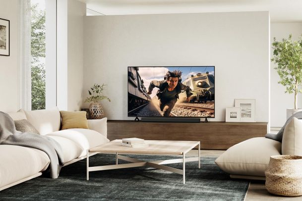 Bright modern living room with a television showing an action scene and a white sofa