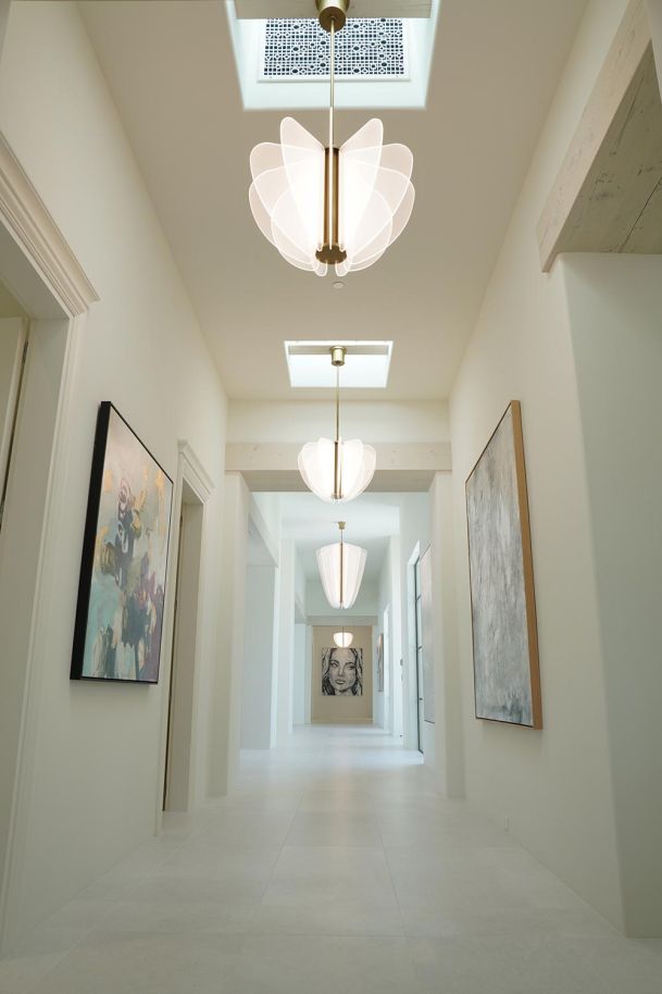 Long white hallway with decorative floral pendant lights and framed artwork