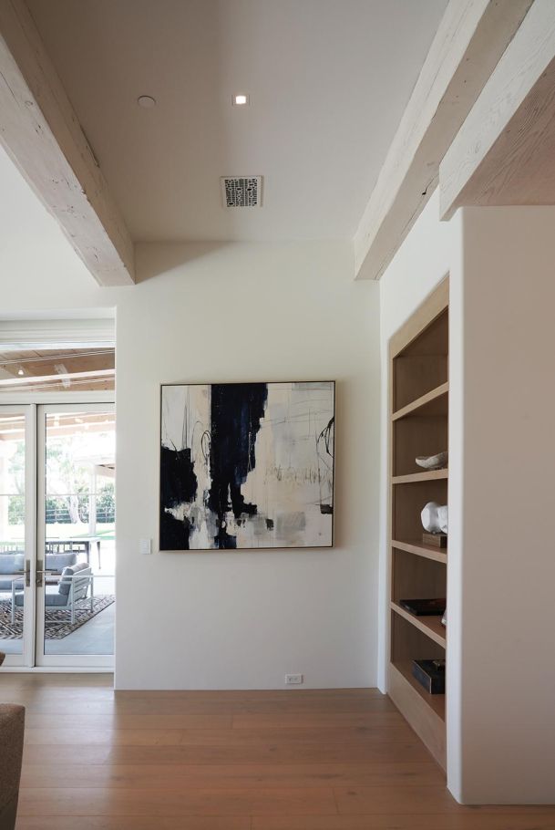 Minimalist hallway featuring abstract art and a built-in wooden bookshelf