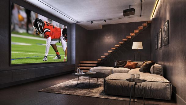 Home theater with a large projection screen showing a football game and a sectional sofa