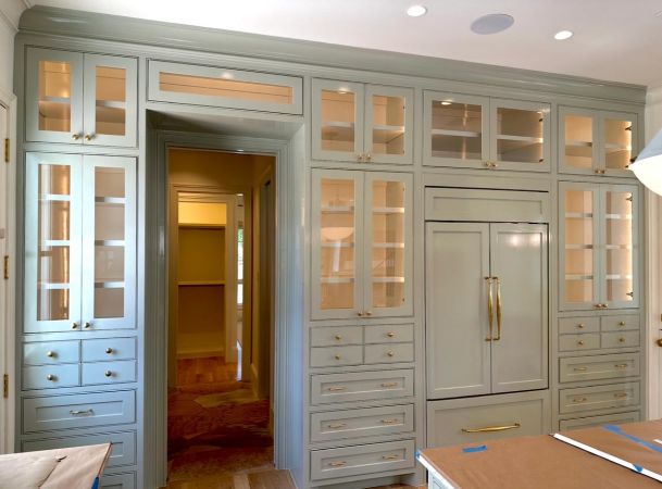 Luxury kitchen featuring sage green floor-to-ceiling cabinetry with built-in refrigerator
