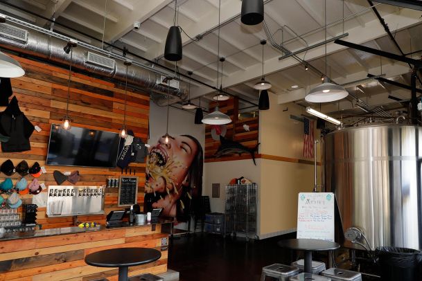 Industrial brewery taproom with a wooden bar and large stainless steel fermentation tank