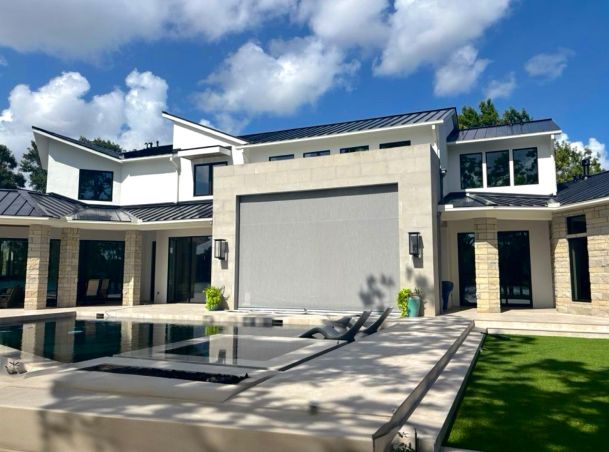 Backyard patio with swimming pool and a large motorized gray shade extended over an patio wall