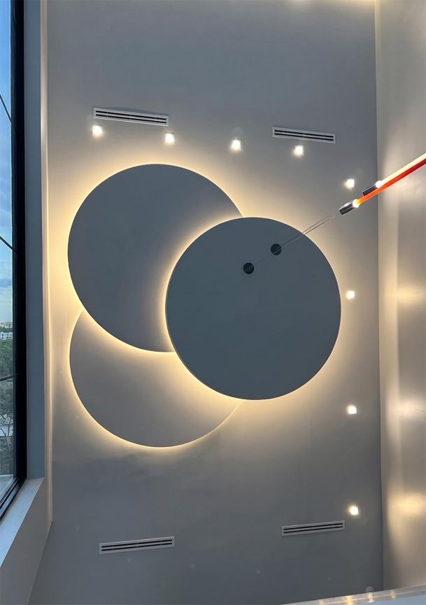 Minimalist wall art featuring overlapping geometric circular panels backlit with warm LEDs