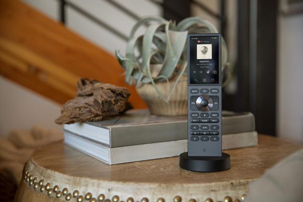 Handheld smart remote in a charging dock resting on a decorative table