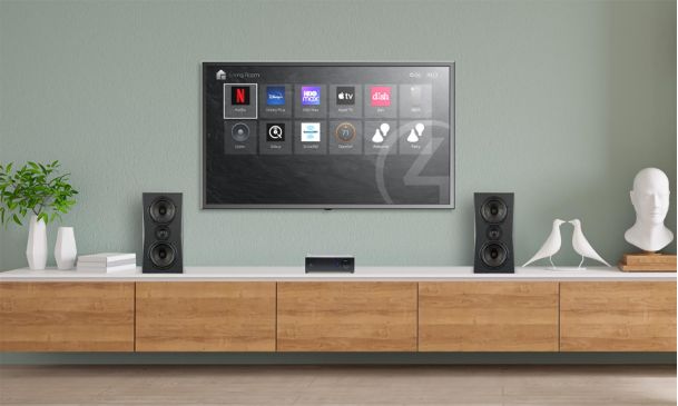 Wall-mounted television showing media app icons above a wooden console and speakers