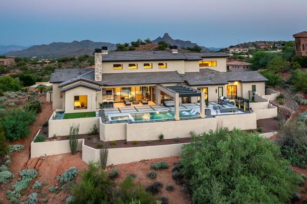 Aerial view of a large desert estate with a pool and outdoor living areas at dusk