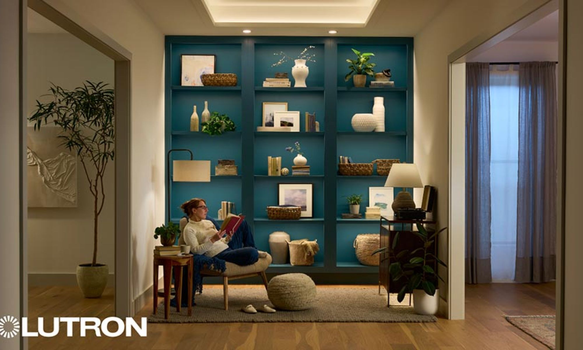 Woman reading in a chair in front of a blue built-in bookshelf with integrated lighting