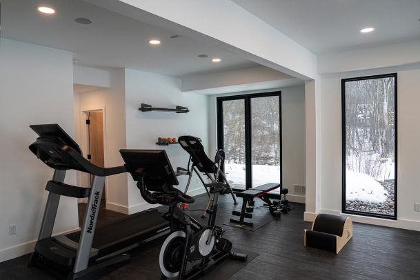 Home gym with a treadmill and stationary bike overlooking a snowy outdoor scene