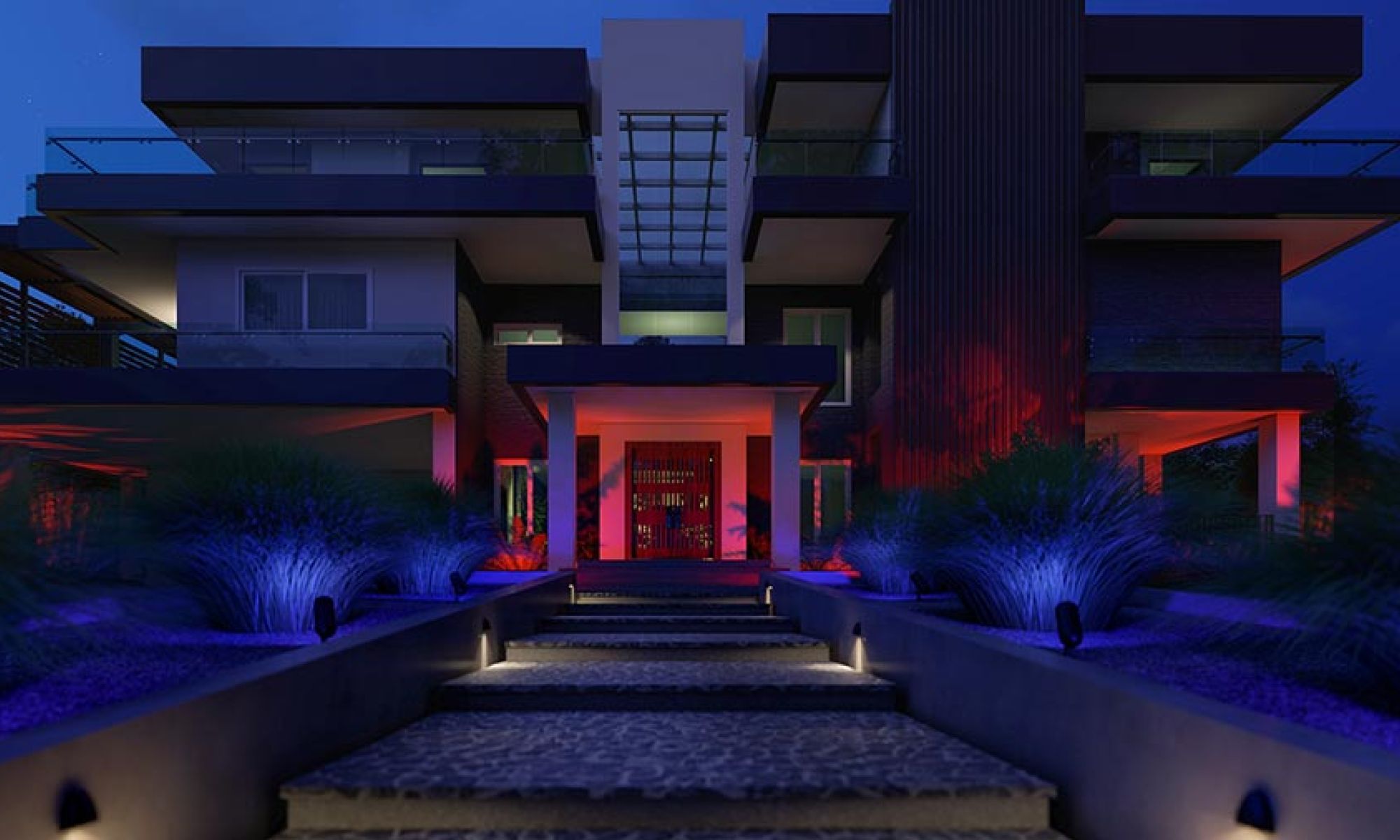 Modern house exterior at night with blue and red accent lighting on landscaping