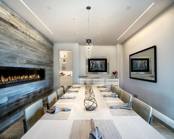 Long formal dining table set for a meal next to a modern linear fireplace