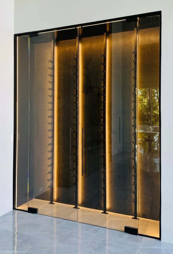 Floor-to-ceiling glass enclosed wine cellar with warm vertical strip lighting