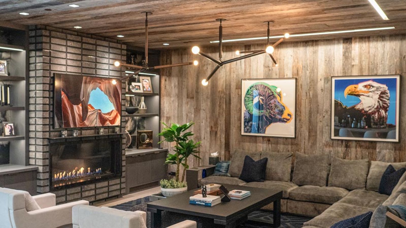 Rustic living area with wood paneled walls, a fireplace, and wall-mounted art