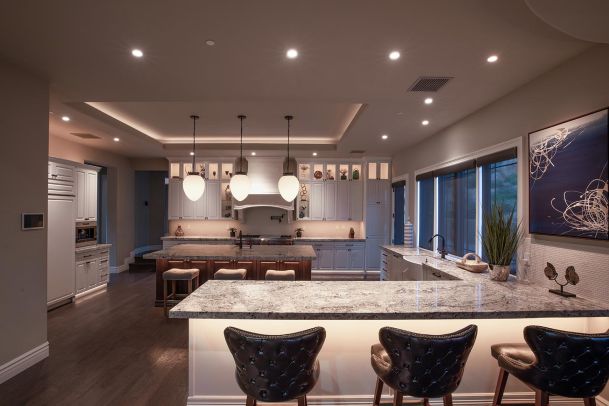 Modern luxury kitchen with island seating and warm recessed lighting at night