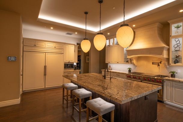 Close-up of a kitchen island with granite countertop and three large pendant lights