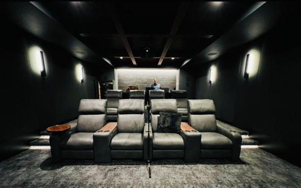 Luxury home theater room with tiered leather recliner seating and soft ambient wall lighting