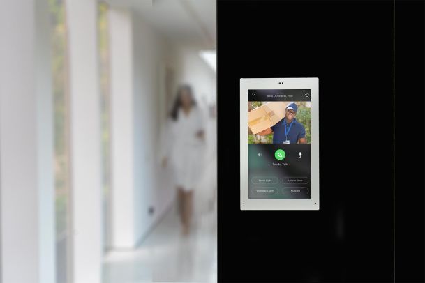Wall-mounted intercom screen showing a delivery person at the front door
