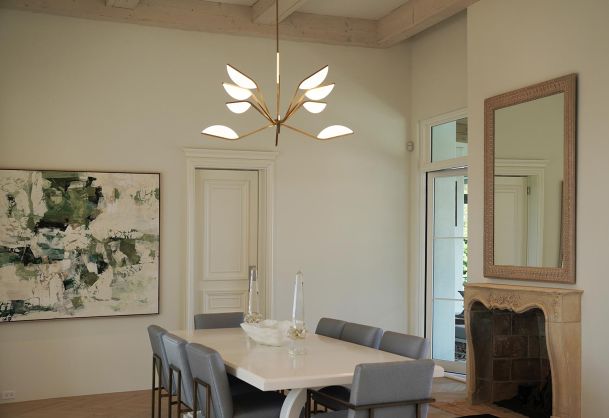 Elegant dining area with a leaf-shaped gold chandelier and a stone fireplace