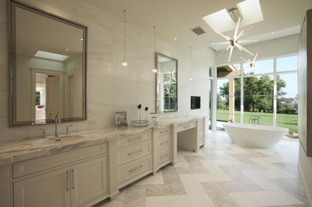 Large luxury bathroom with marble counters and a white soaking tub by a window