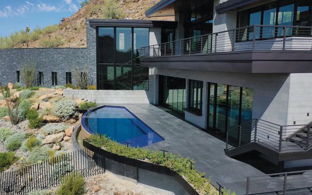 Modern hillside home with a blue infinity pool and glass railings